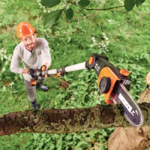 Jardinero cortando una rama de árbol con un kit pértiga y mini motosierra worx 